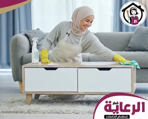 تقديم طلب تأشيرة عمل قطر 30699789 الرعاية عاملة تنظيف محترفة تقوم بتنظيف طاولة خشبية بعناية باستخدام منظف وقطعة قماش للحفاظ على النظافة.